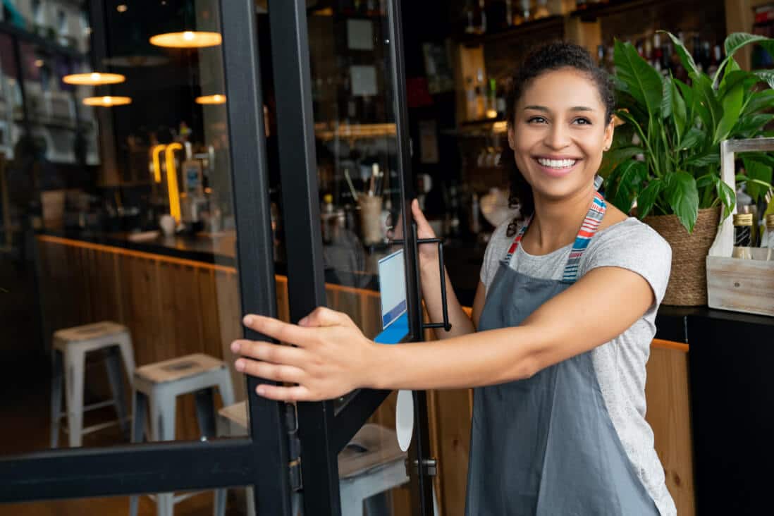 woman opening door to her shop